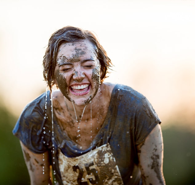 woman smiling after a muddy run