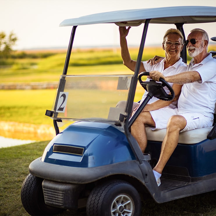 mature couple driving golf cart at Glynnlea Wylder