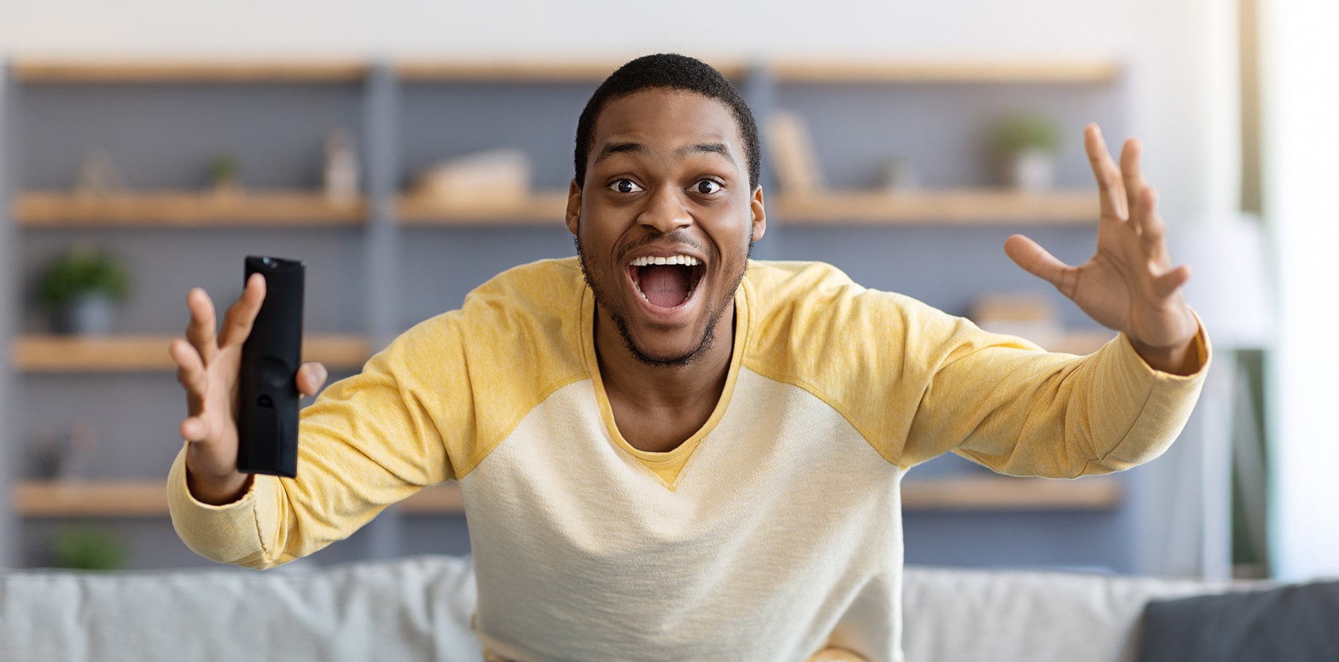 man excited about sports with remote in hand