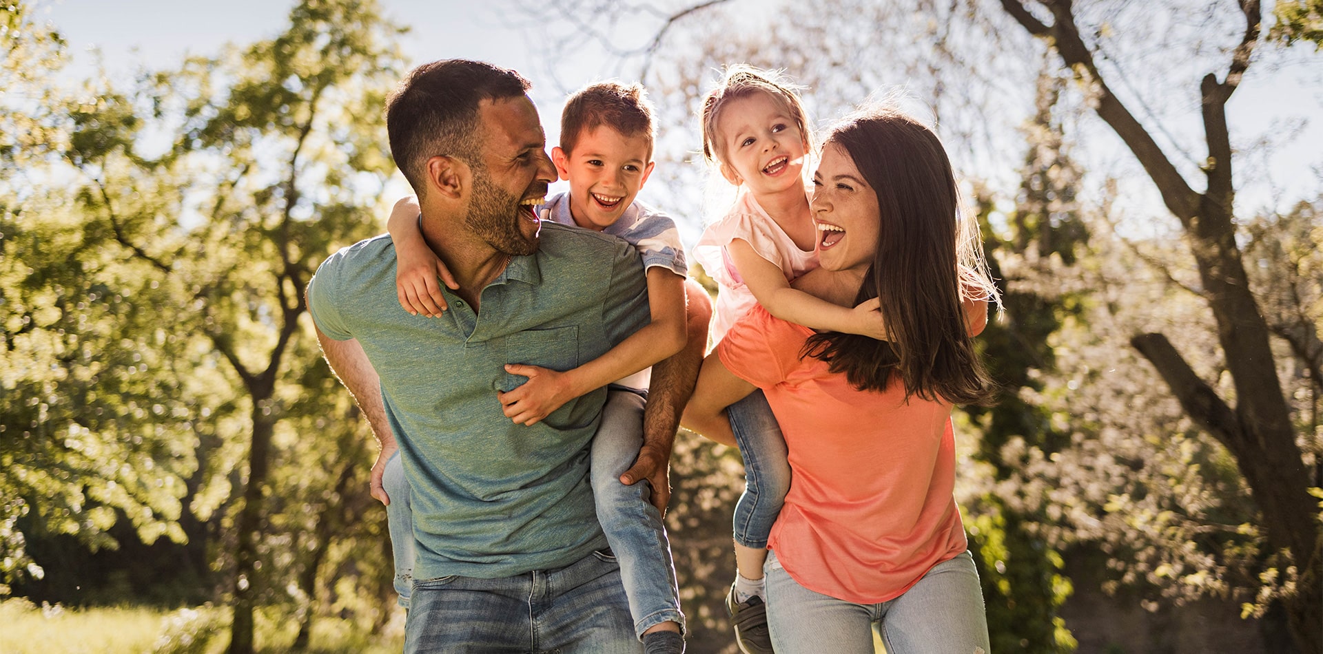 couple giving their kids a piggy back ride walking through trails in port st lucie