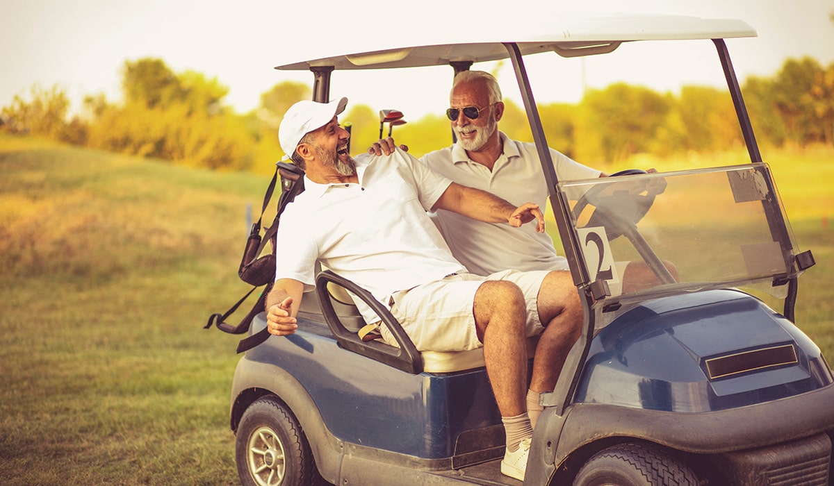 men riding golf cart together