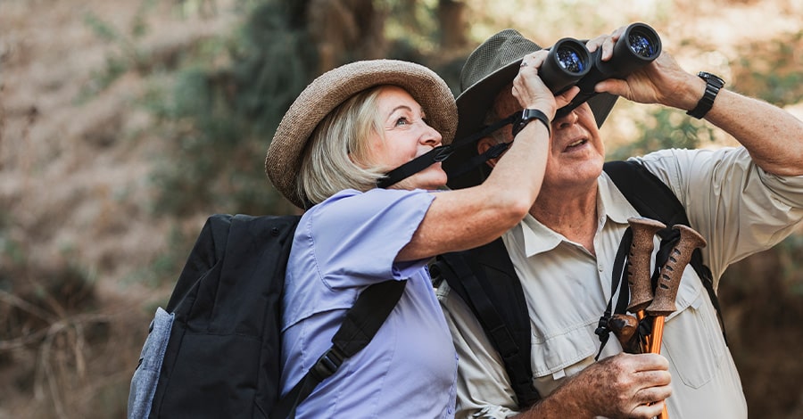 Mature Couple Hiking and looking through Binoculars