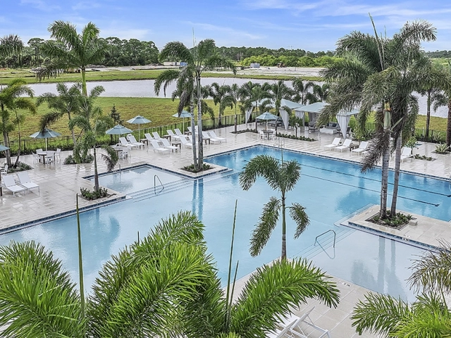 Resort-style pool and cabana seating surrounded by palm trees at Wylder Port St. Lucie