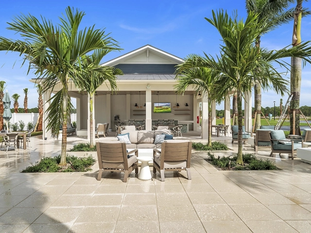 Outdoor lounge seating with palm trees at Wylder Port St. Lucie clubhouse