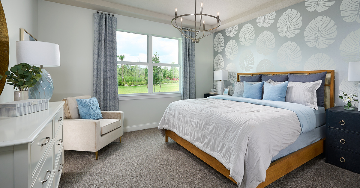 Bedroom with upholstered bed, patterned accent wall, and window view.