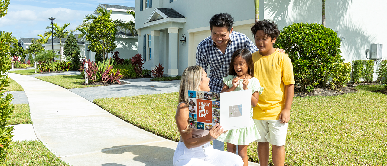 Family stands on sidewalk outside home while reviewing a brochure together.
