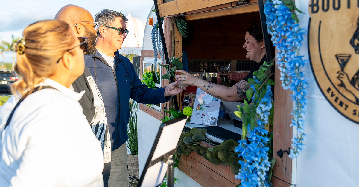 People ordering drinks at decorated outdoor beverage trailer.