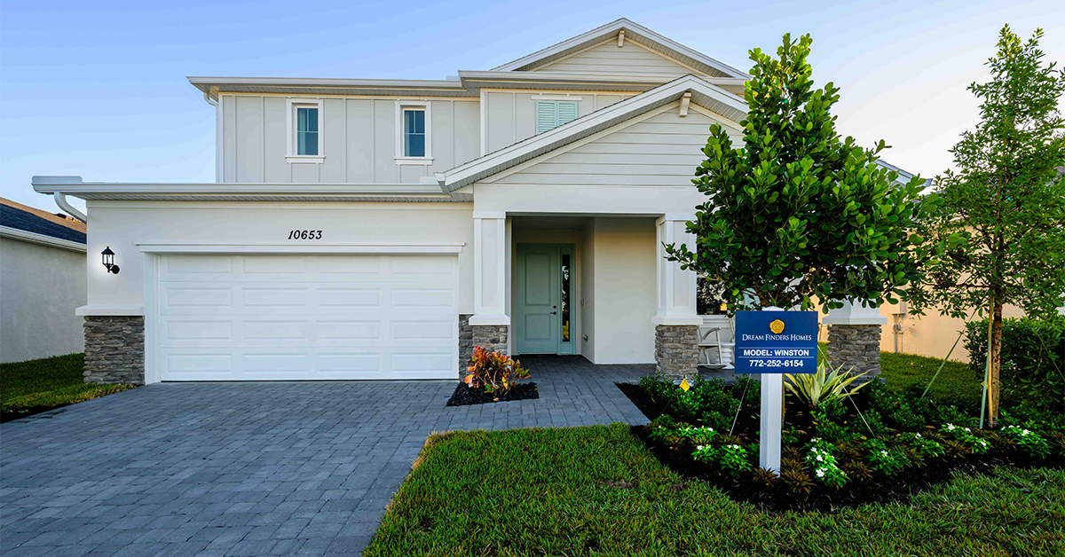 Two-story model home with driveway and yard landscaping.