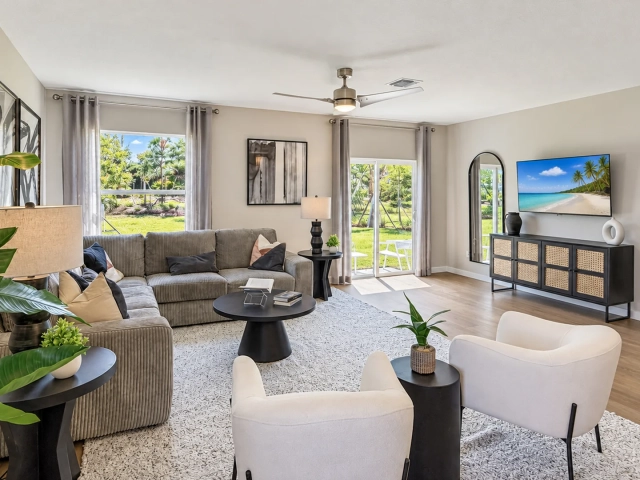 Living room with a gray corduroy sectional sofa, a wall-mounted TV between two arched mirrors, and sliding glass doors.