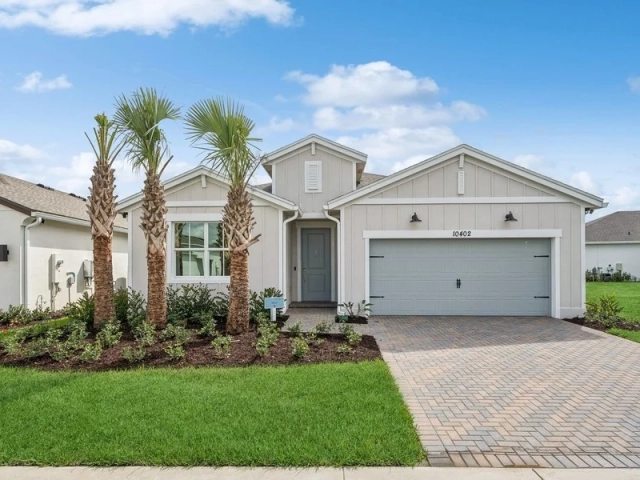 Single-story light gray model home with a two-car garage, board-and-batten siding, and tall palm trees near the entry, address 10402.