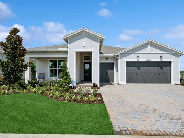 Single-story light gray model home with two dark charcoal garage doors and a paver driveway, address 10345.