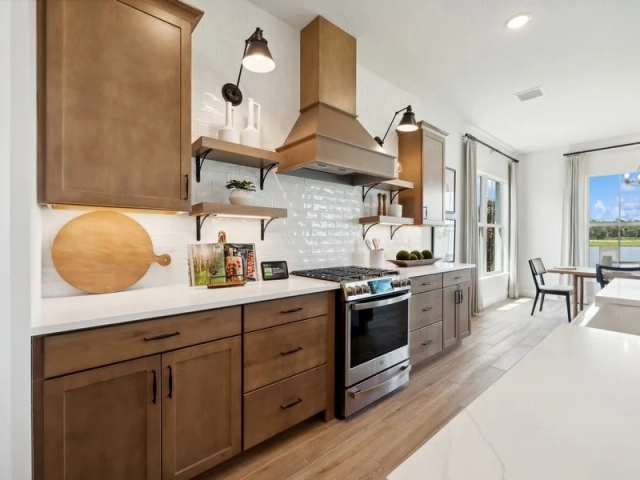 Kitchen with wood cabinets, a brass range hood, white subway tile backsplash, and a stainless steel gas range.