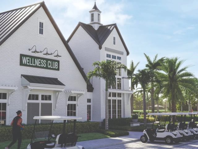 Rendering of a white brick building with a Wellness Club sign, tall windows, and a row of white golf carts parked outside.