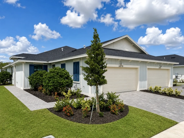 Single-story light blue-gray model home with navy shutters and a cream garage door, address 10779.