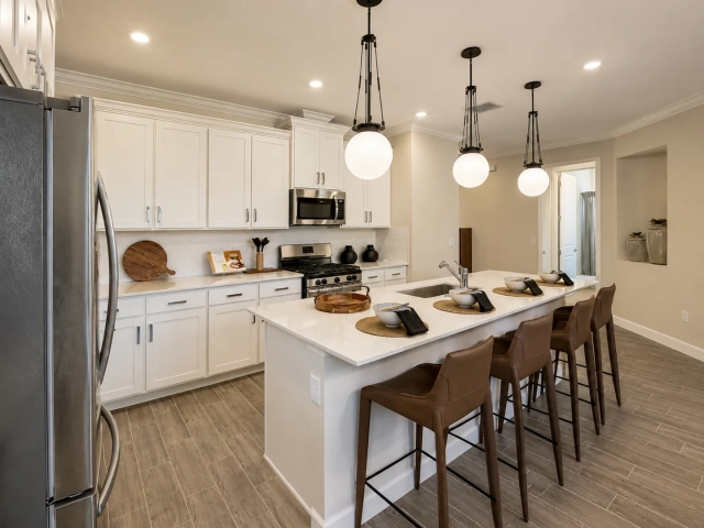 Kitchen with white cabinets, stainless steel appliances, globe pendant lights, and a long island with brown leather barstools.