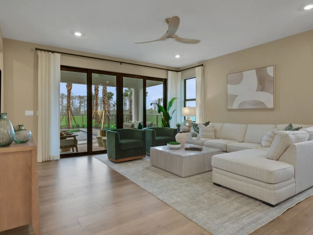 Living room with a large cream sectional sofa, two green accent chairs, and sliding glass doors opening to an outdoor patio.